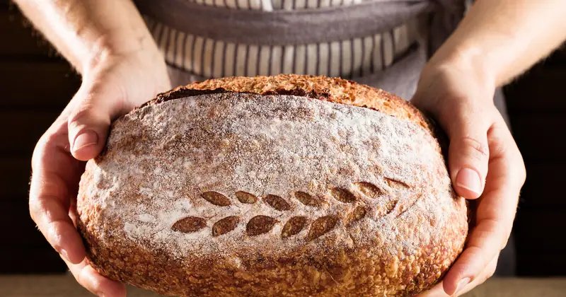 Stock photograph of a patterned loaf held in an artisan kitchen.