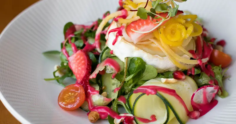 A colourful vegetable salad with cheese on a ceramic plate.